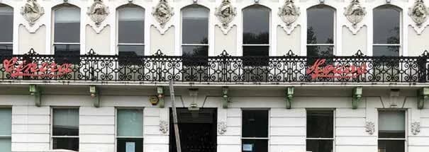 Detail of the first-floor terracotta heads between arched windows above the cast-iron balcony