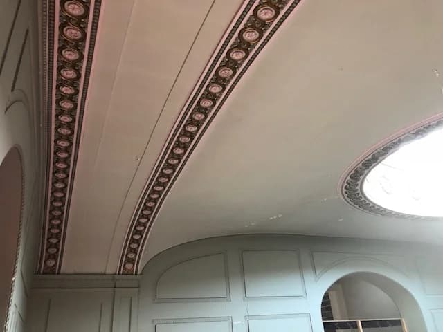 Decorative ceiling mouldings beside an oval glazed opening