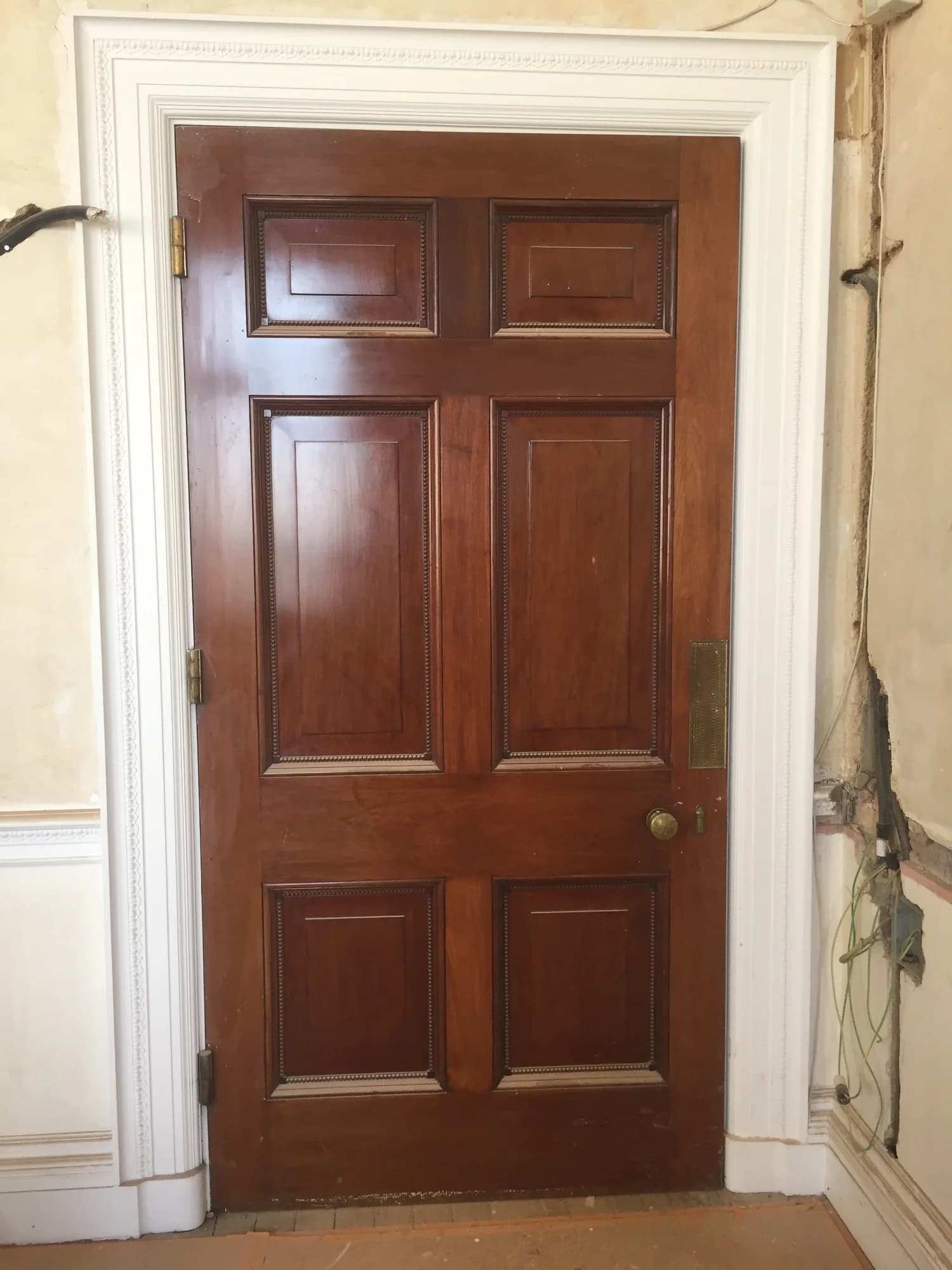 A polished panelled timber door with a pale decorative surround